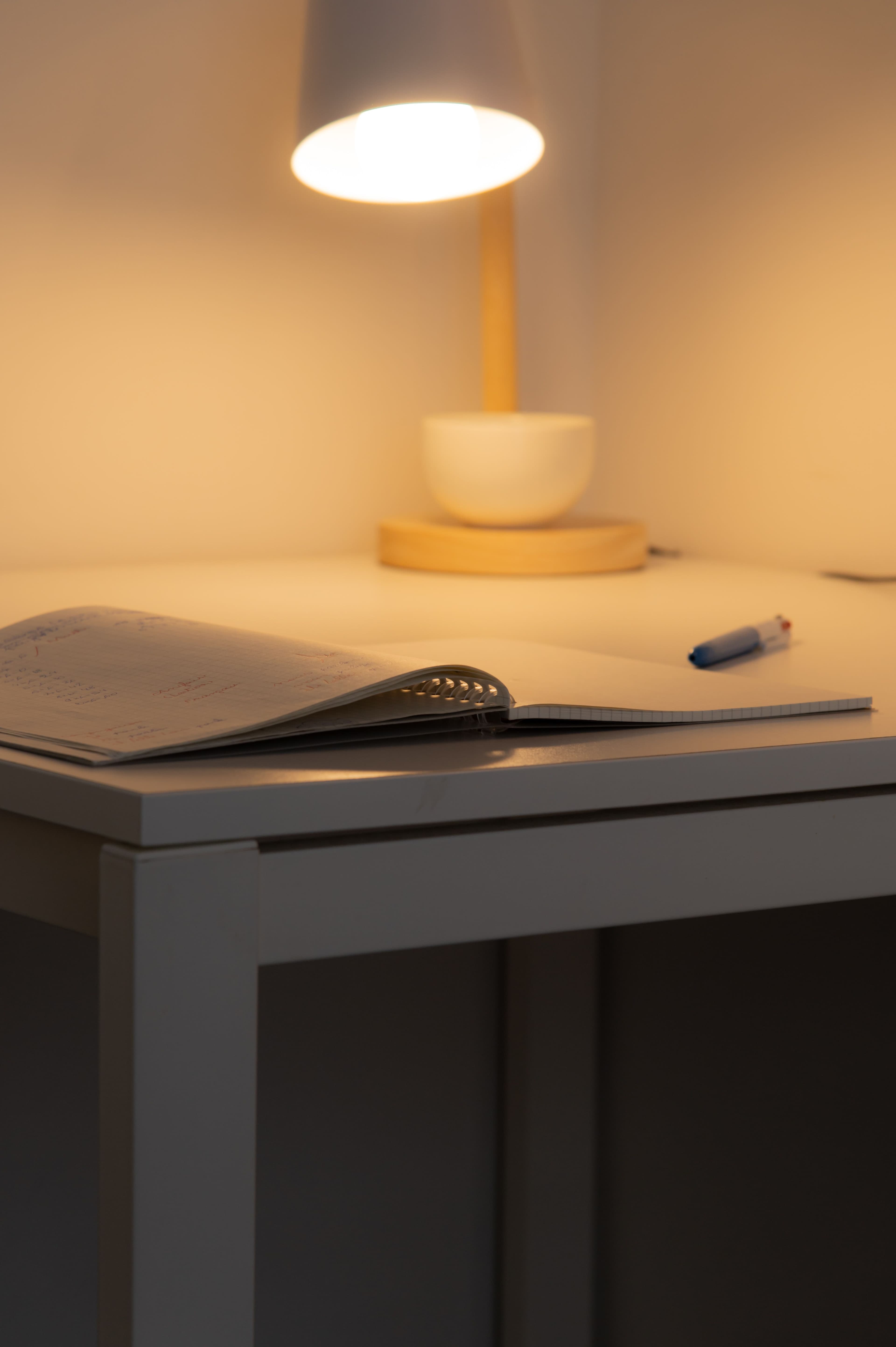 A notebook open under a warm desk lamp, late in the evening